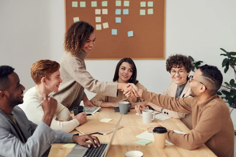 Réunion de travail autour d'un tableau de suivi, poignée de main entre deux collaborateurs